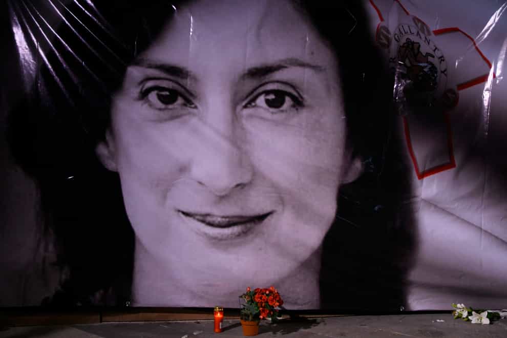 Flowers and a candle lie in front of a portrait of investigative journalist Daphne Caruana Galizia in Matla (Jonathan Borg/AP)