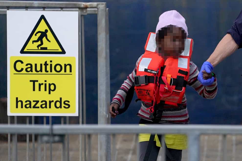 A young girl is escorted by a Border Force officer as a group of people thought to be migrants are brought in to Dover, Kent (PA)