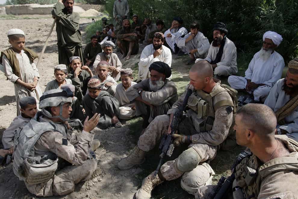 A translator for US Marines speaks with Afghan villagers in Helmand province (David Guttenfelder/AP)