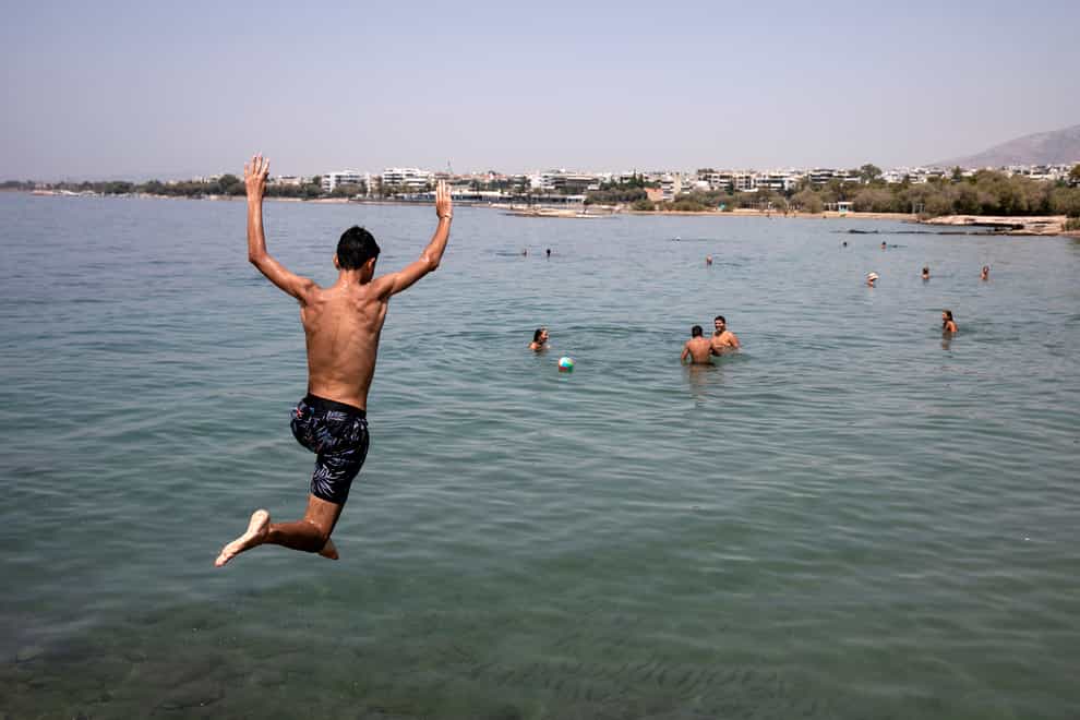 A youth jumps in the sea at a beach of Kavouri suburb, south-west of Athens (Yorgos Karahalis/AP)