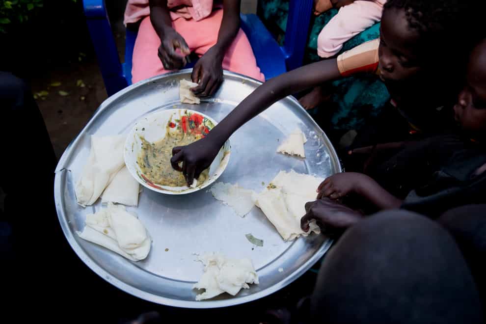 A mother shares a meal with her family at her Juba, South Sudan home (Adrienne Surprenant/PA)