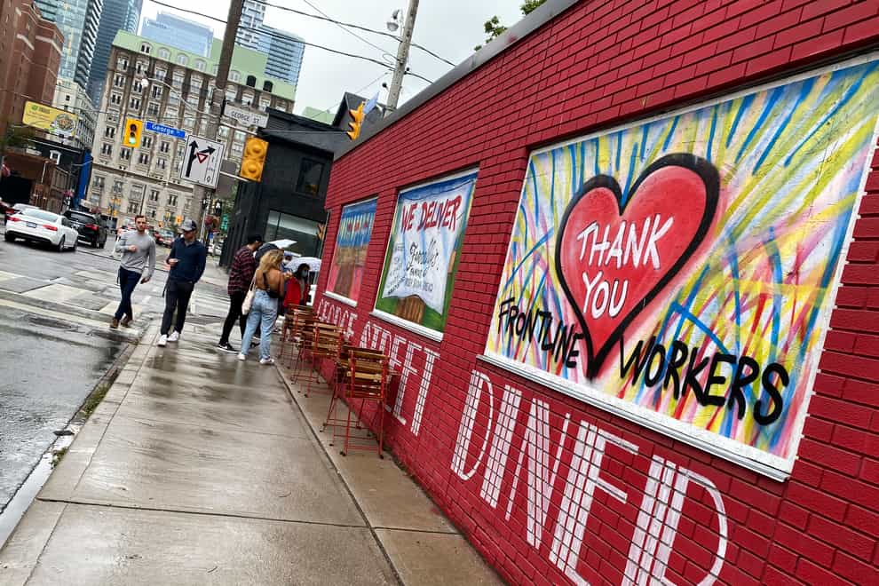 People line up to dine at a restaurant that has painted its walls to support the frontline workers in Toronto, Canada (Kamran Jebreili/AP)