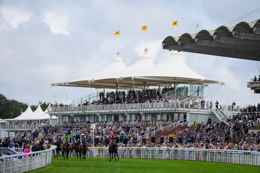 A general view of the racing in front of busy stands at Goodwood (John Walton/PA)