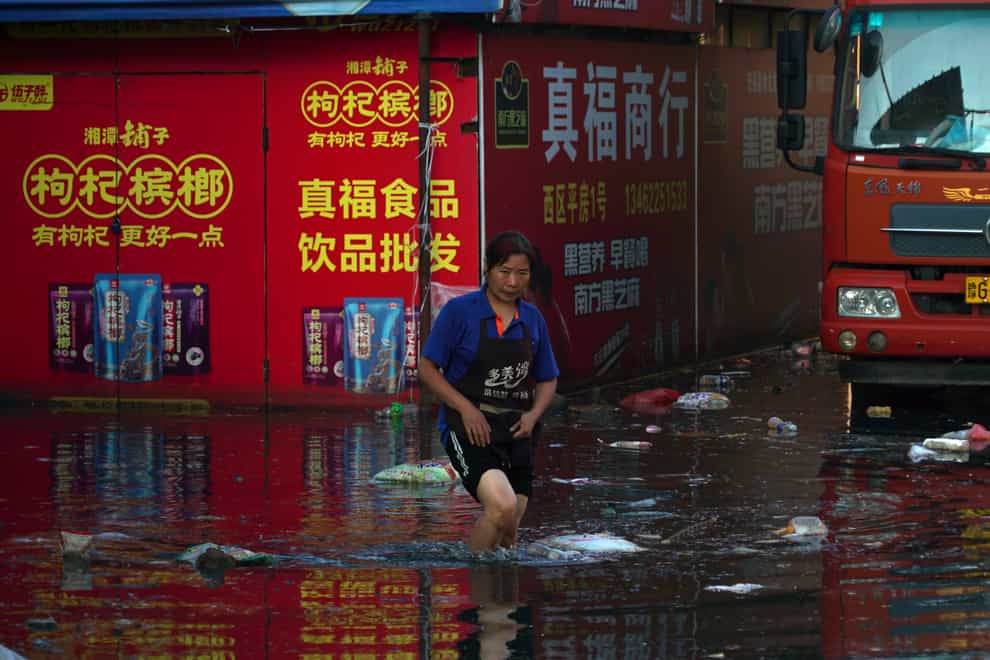 Xing, a shop owner at Yubei Agricultural and Aquatic Products World, walks in floodwaters at the market in Xinxiang in central China’s Henan Province (Dake Kang/AP)