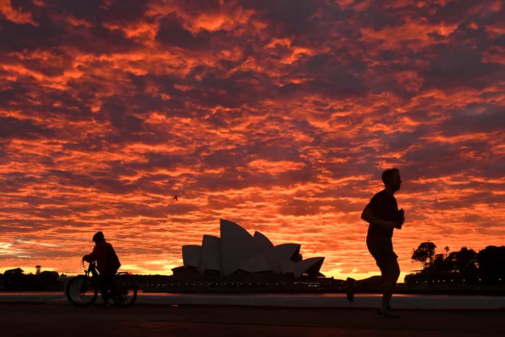 A jogger runs past the Sydney Opera House at dawn (Mick Tsikas/AAP Image via AP)