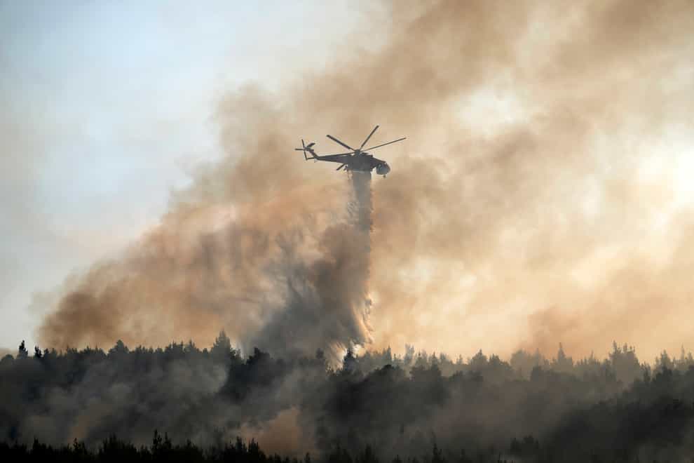 An helicopter drops water over a fire in Varibobi area, northern Athens, Greece, Wednesday, Aug. 4, 2021. Firefighting planes were resuming operation at first light Wednesday to tackle a major forest fire on the northern outskirts of Athens which raced into residential areas the previous day, forcing thousands to flee their homes amid Greece’s worst heatwave in decades. (AP Photo/Thanassis Stavrakis)