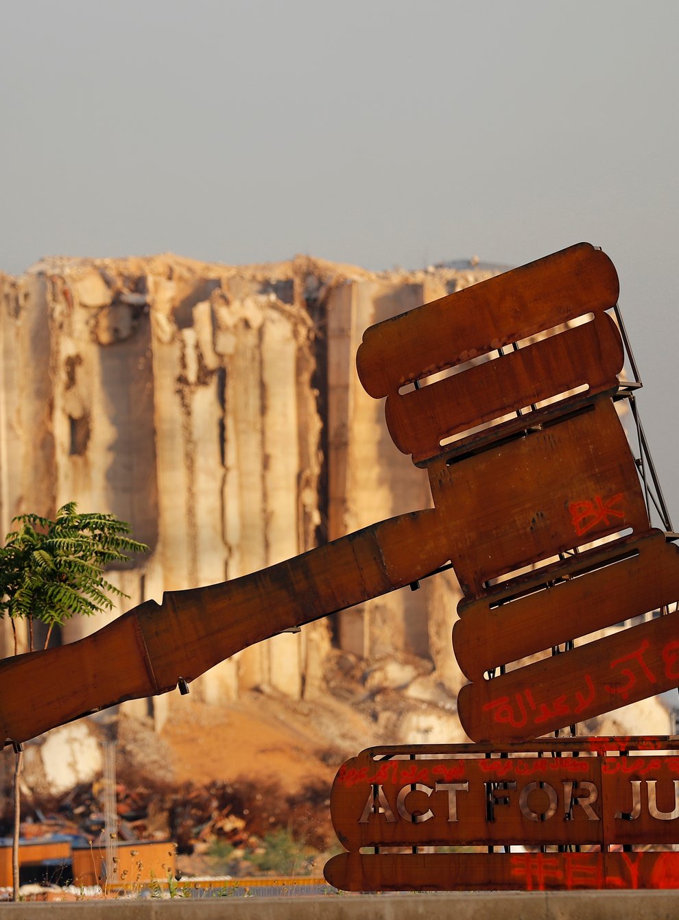 A justice symbol monument is seen in front of towering grain silos that were gutted in the massive August 2020 explosion at the port that claimed the lives of more than 200 people, in Beirut, Lebanon (Hussein Malla/AP)
