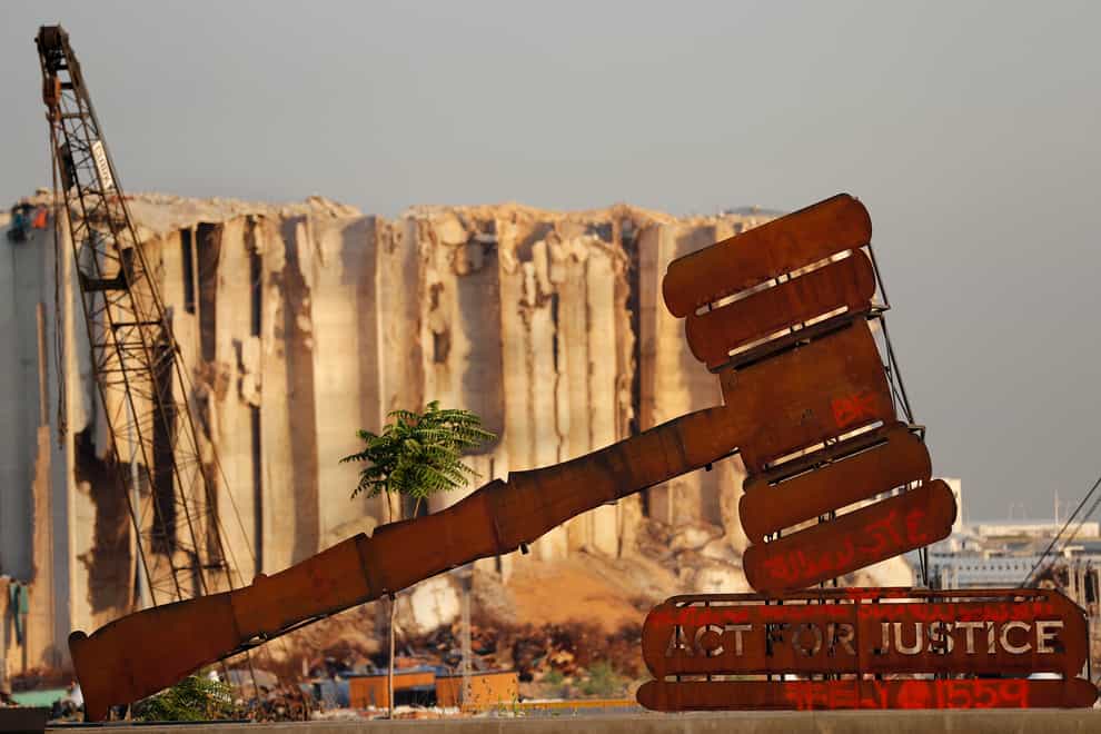 A justice symbol monument is seen in front of towering grain silos that were gutted in the massive August 2020 explosion at the port that claimed the lives of more than 200 people, in Beirut, Lebanon (Hussein Malla/AP)