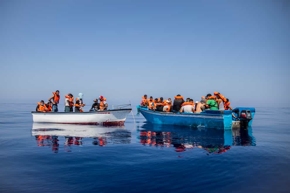 A group await on board precarious wooden boats around 20 miles southwest from the Italian island of Lampedusa (Santi Palacios/AP)