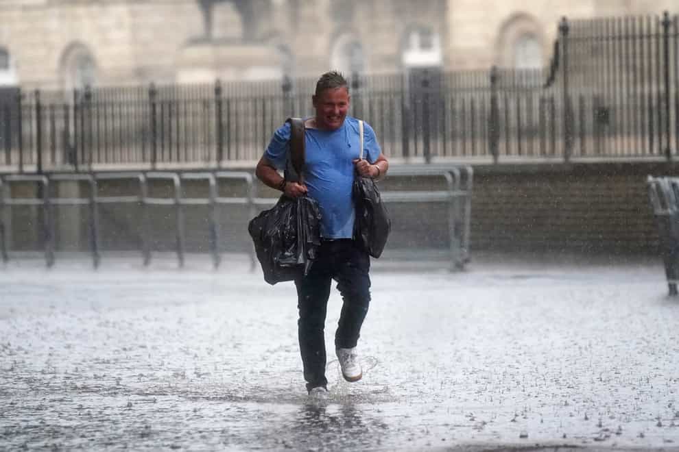 A man walks through flood water in in central London. Thunderstorms are being forecast (PA)
