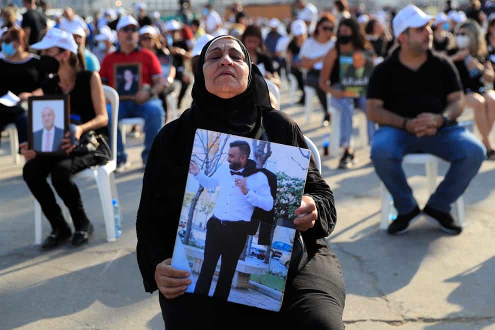 A woman holds a picture of her son, who was killed in the massive blast last year at the Beirut port (Hussein Malla/AP)