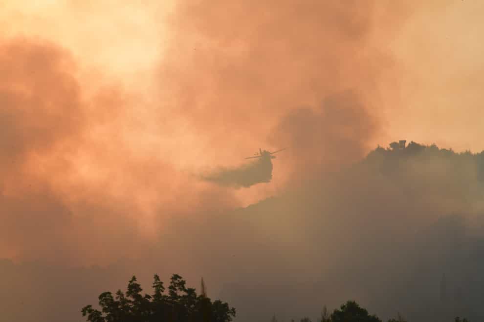 An aircraft drops water during a wildfire in ancient Olympia (Giannis Spyrounis/ilialive.gr via AP)