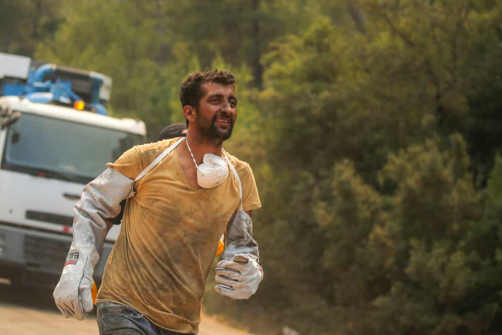 A Turkish volunteer runs as they head to fight wildfires in Turgut village (AP)