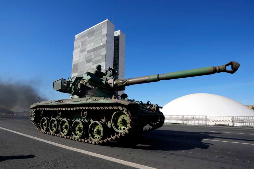 A tank drives past Congress as part of a convoy after it passed by Planalto presidential palace in Brasilia, Brazil, Tuesday, Aug. 10, 2021. The convoy paraded by the palace on Tuesday, the day of a key congressional vote on a constitutional reform proposal supported by Bolsonaro that would add printed receipts to some of the nation’s electronic ballot boxes. (AP Photo/Eraldo Peres)