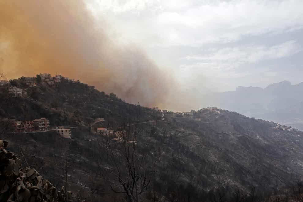 Smoke and fires threaten a village near Tizi Ouzou some 100 km (62 miles) east of Algiers following wildfires in this mountainous region, Tuesday, Aug.10, 2021. Firefighters were battling a rash of fires in northern Algeria that have killed at least six people in the mountainous Kabyle region, the interior minister said Tuesday, accusing “criminal hands” for some of the blazes. (AP Photo/Fateh Guidoum)