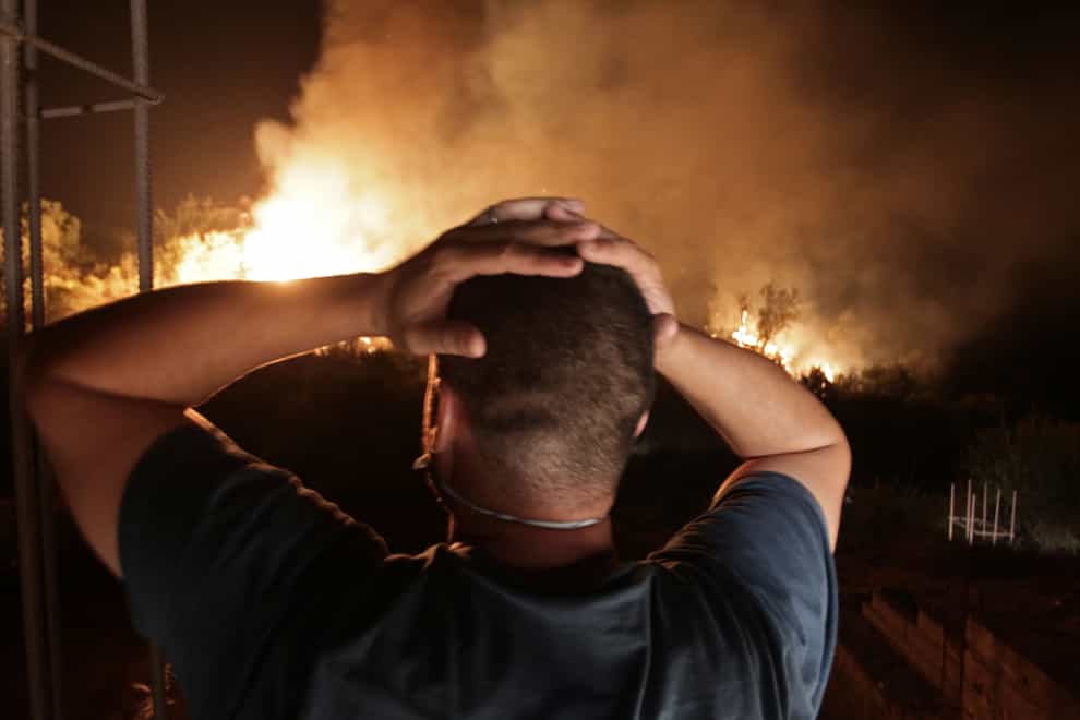 A man watches in horror as a forest fire rips through a village in the Kabyle region (Fateh Guidoum/AP)