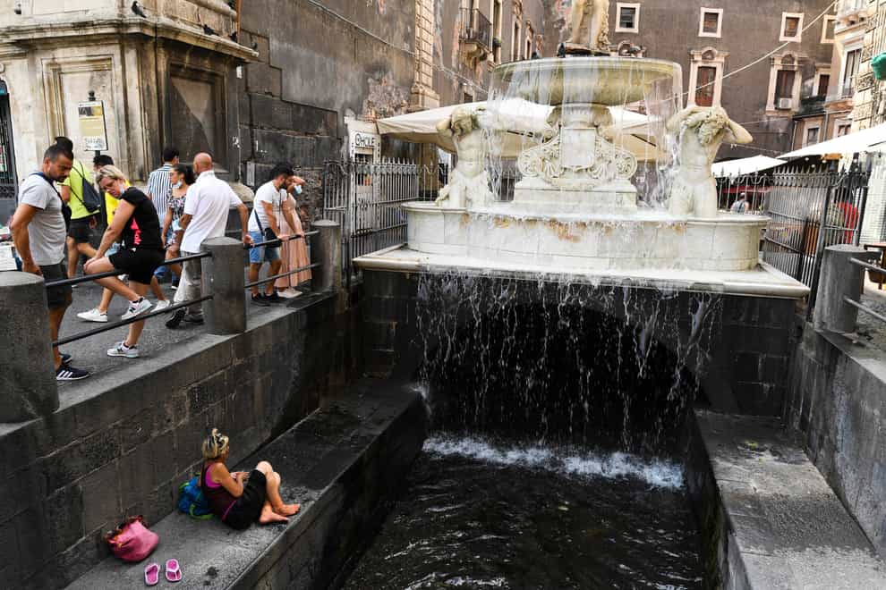 A woman sits near a fountain in a street of Catania, Sicily (Salvatore Cavalli/AP)