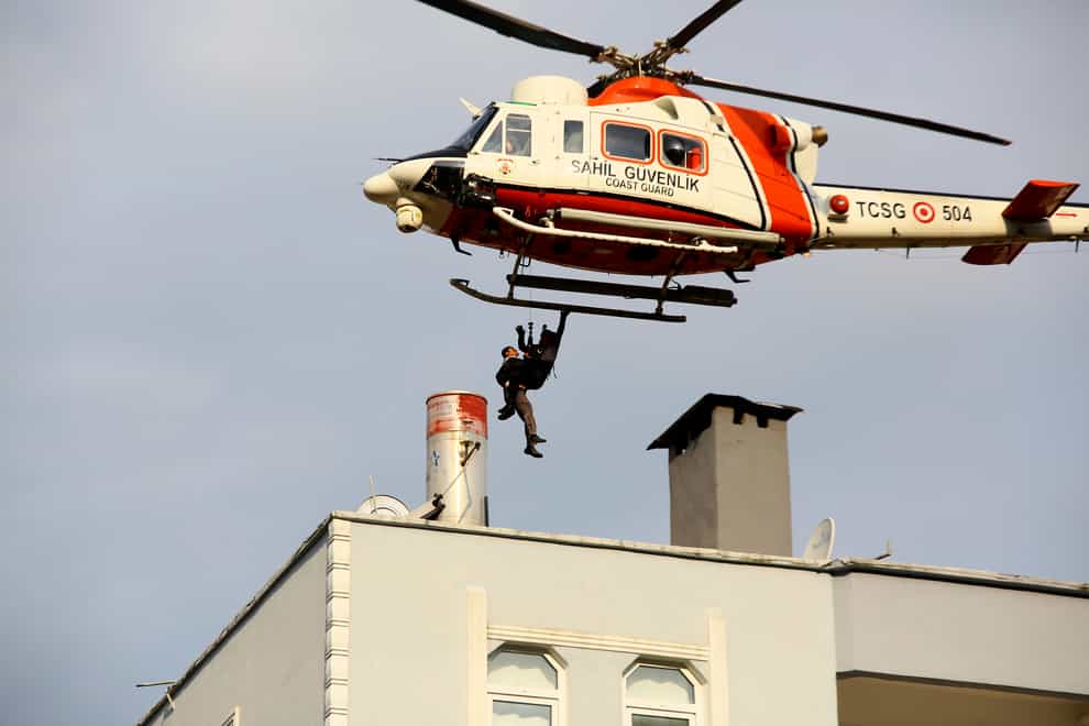 A Coast Guard helicopter rescues a man stranded on a rooftop in Bozkurt, Turkey (IHA via AP)