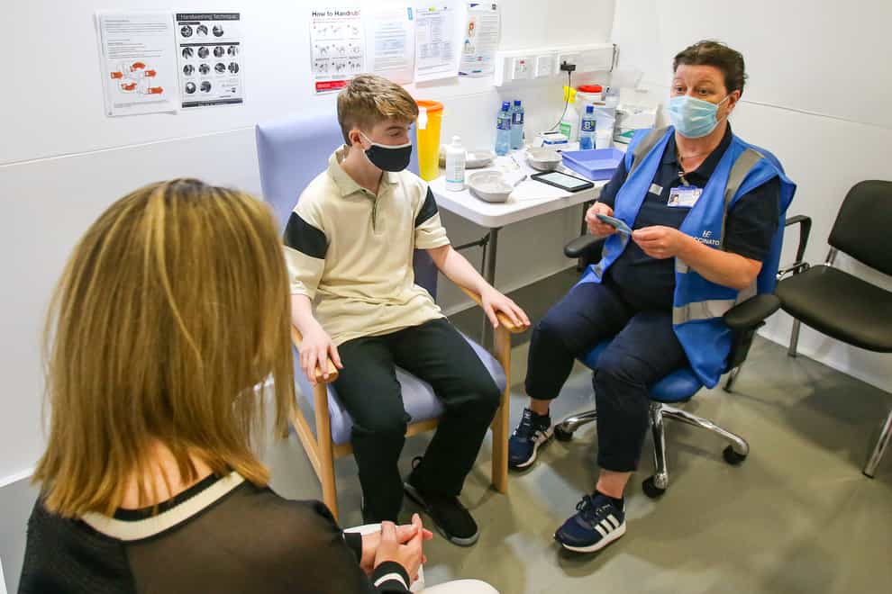Denise O’Mahony McKeon with her son Kevin Mckeon, 14, as she speaks to vaccinator Geraldine Flynn before he receives his first dose of the Covid-19 vaccine at the Citywest vaccination centre in Dublin (Damien Storan/PA)