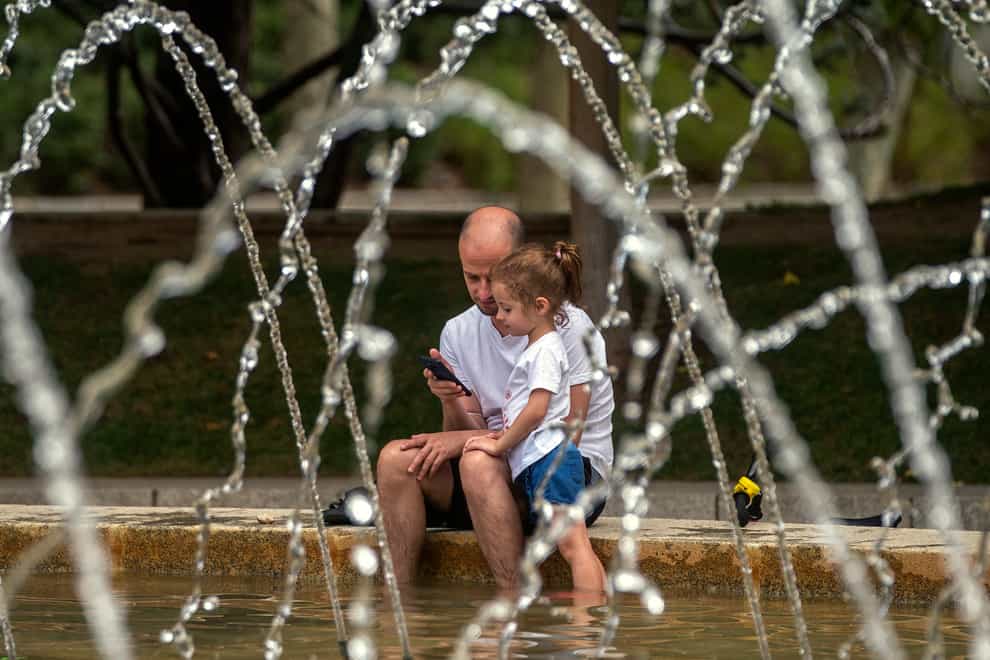 A man and a girl cool off in a fountain in Madrid (Andrea Comas/AP)