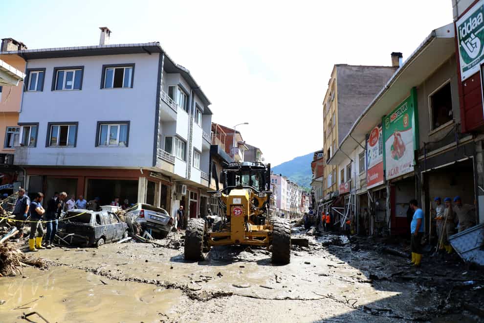 Workers clear the mud from a street in Bozkurt (AP)