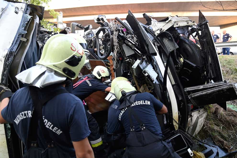 Firefighters check out the wrecked bus which flipped over and crashed (Zoltan Mihadak/MTI via AP)