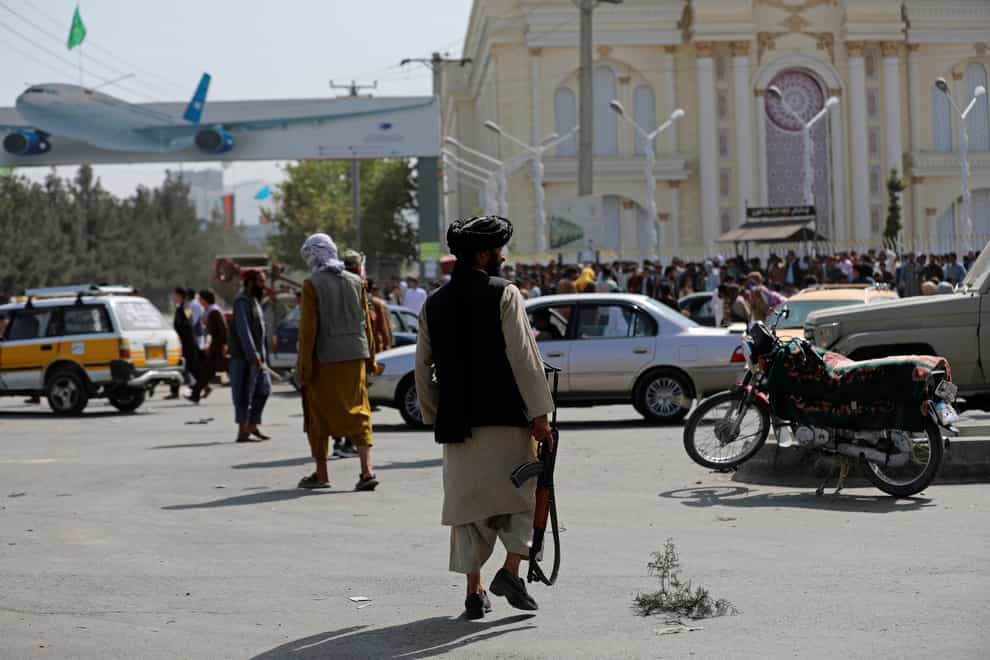 Taliban fighters stand guard in front of the Hamid Karzai International Airport, where thousands gathered on Sunday night and Monday morning (Rahmat Gul/AP)