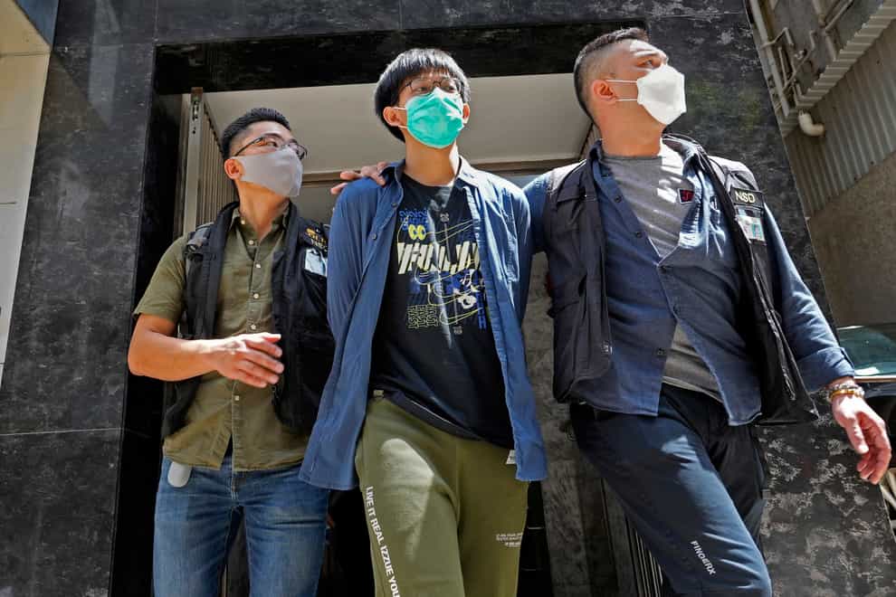 A student of Hong Kong University, centre, is escorted by police officers after a home search in Hong Kong (Vincent Yu/AP)