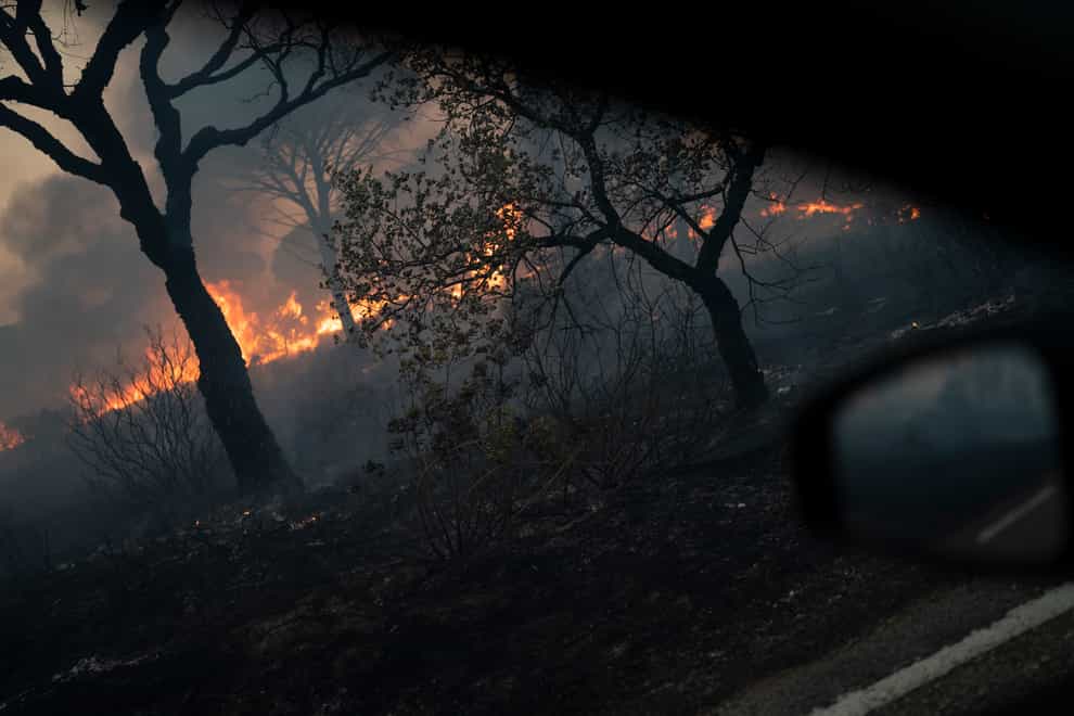 A burning forest is pictured from a car window near Le Luc, southern France (Daniel Cole/AP)