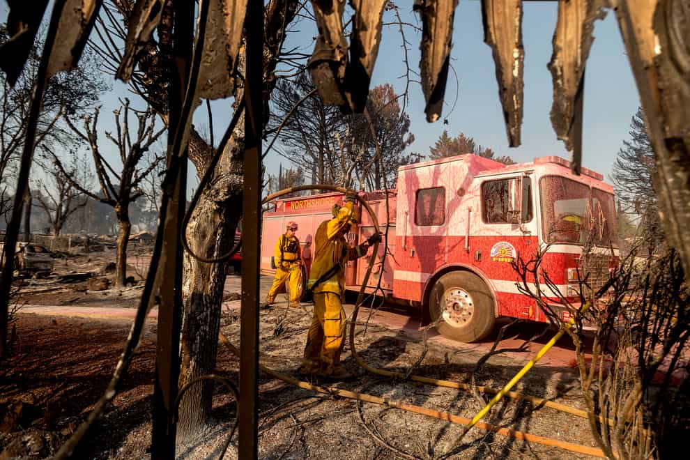 Firefighters mop up at Cache Creek Mobile Home Estates where the Cache Fire levelled dozens of residences (Noah Berger/AP)