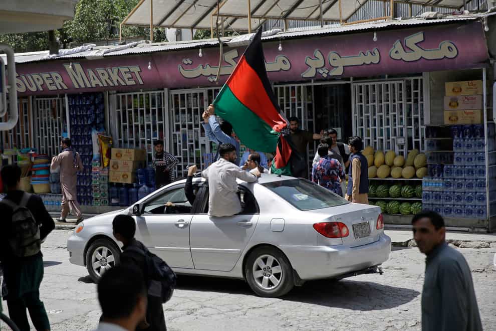 Afghans wave a black, red and green banner in honour of the Afghan flag — a banner that is becoming a symbol of defiance since the Taliban have their own flag, on Afghan Independence Day, in Kabul, Afghanistan (Rahmat Gul/AP)