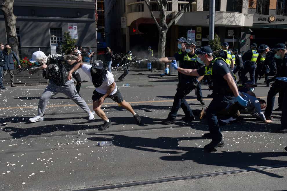 Police use pepper spray on protesters during an anti-lockdown protest in Melbourne, Australia, Saturday, Aug. 21, 2021. Protesters are rallying against government restrictions placed in an effort to reduce the COVID-19 outbreak. (James Ross/AAP Image via AP)