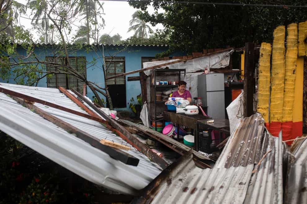 A woman begins clearing debris from her kitchen after a part of her home was damaged by winds brought on by Hurricane Grace, in Tecolutla, Veracruz State, Mexico, on Saturday (Felix Marquez/AP)