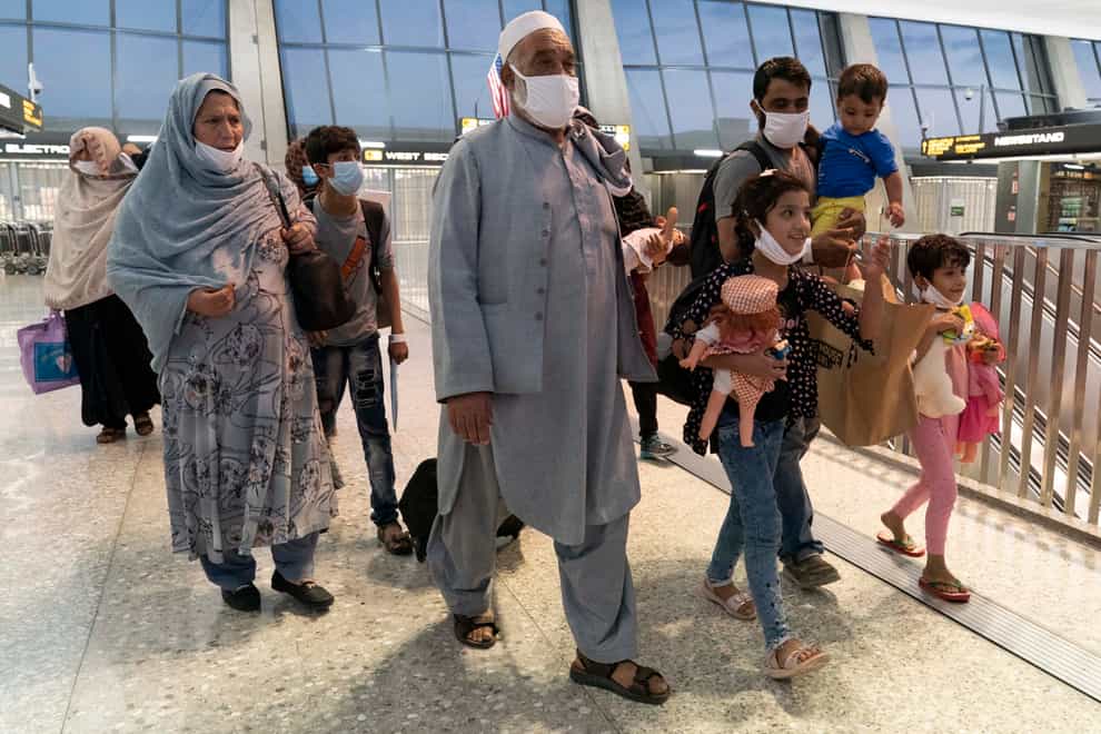 Families evacuated from Kabul, Afghanistan, walk through the terminal before boarding a bus after they arrived at Washington Dulles International Airport, in Chantilly, Virginia (Jose Luis Magana/AP)