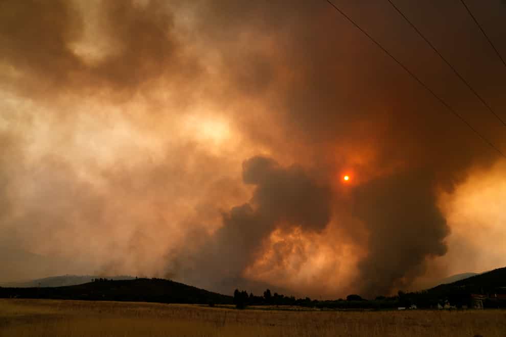 A wildfire burns a forest in Vilia area some 60 kilometers (37 miles) northwest of Athens, Greece, Wednesday, Aug. 18, 2021. A major wildfire northwest of the Greek capital devoured large tracts of pine forest for a third day and threatened a large village as hundreds of firefighters, assisted by water-dropping planes and helicopters, battled the flames Wednesday. (AP Photo/Thanassis Stavrakis)