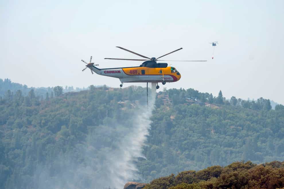 A Croman Sikorsky S-61A helicopter drops water on the south end of the Caldor Firein California (Sara Nevis/The Sacramento Bee via AP)