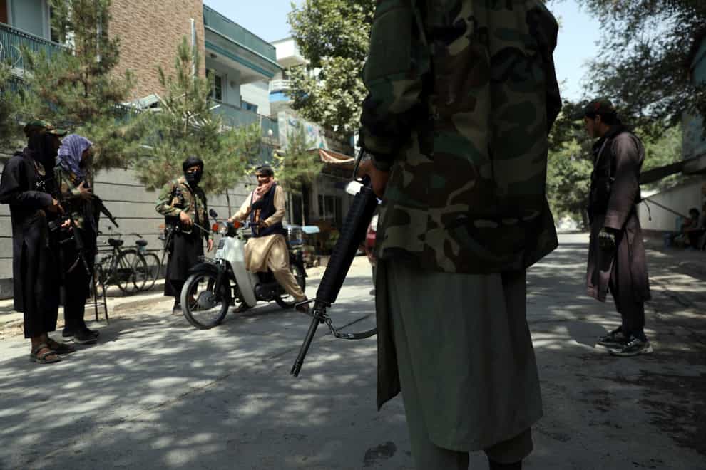 Taliban fighters stand guard at a checkpoint (Rahmat Gul/AP)