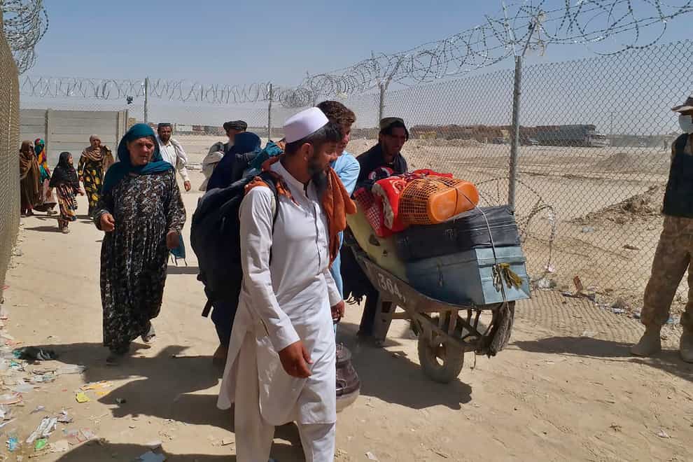 Afghan families enter Pakistan through a border crossing (Jafar Khan/AP)