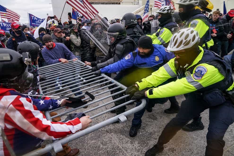 Violent insurrectionists loyal to Donald Trump hold on to a police barrier at the Capitol in Washington on January 6 (AP)
