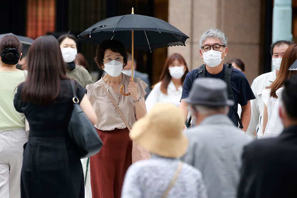 People wearing face masks to help protect against the spread of the coronavirus walk across an intersection (AP)