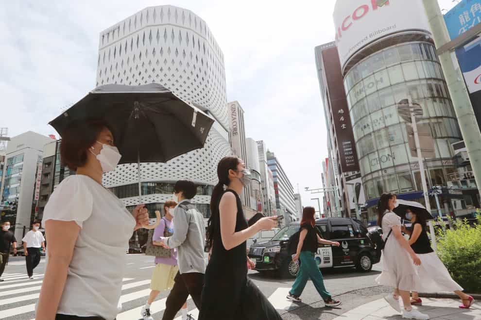 People wearing face masks walk along a street in Tokyo (Koji Sasahara/AP)