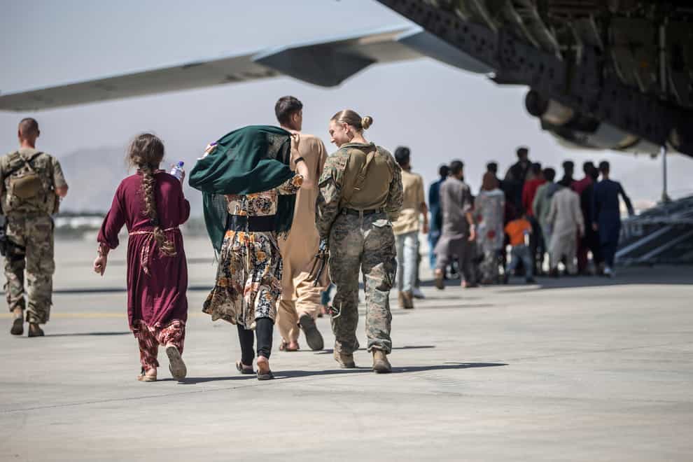 A Marine walks with a family during ongoing evacuations at Hamid Karzai International Airport, Kabul, Afghanistan (Sgt Samuel Ruiz/US Marine Corps via AP)