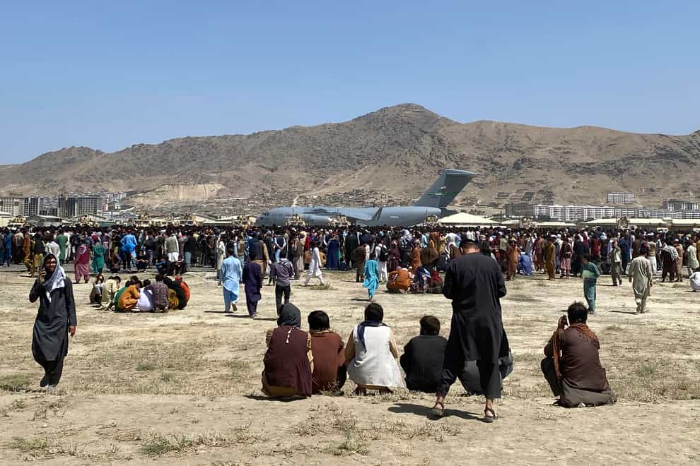 Hundreds of people gather near a plane at the perimeter of the international airport in Kabul, Afghanistan (Shekib Rahmani/AP)