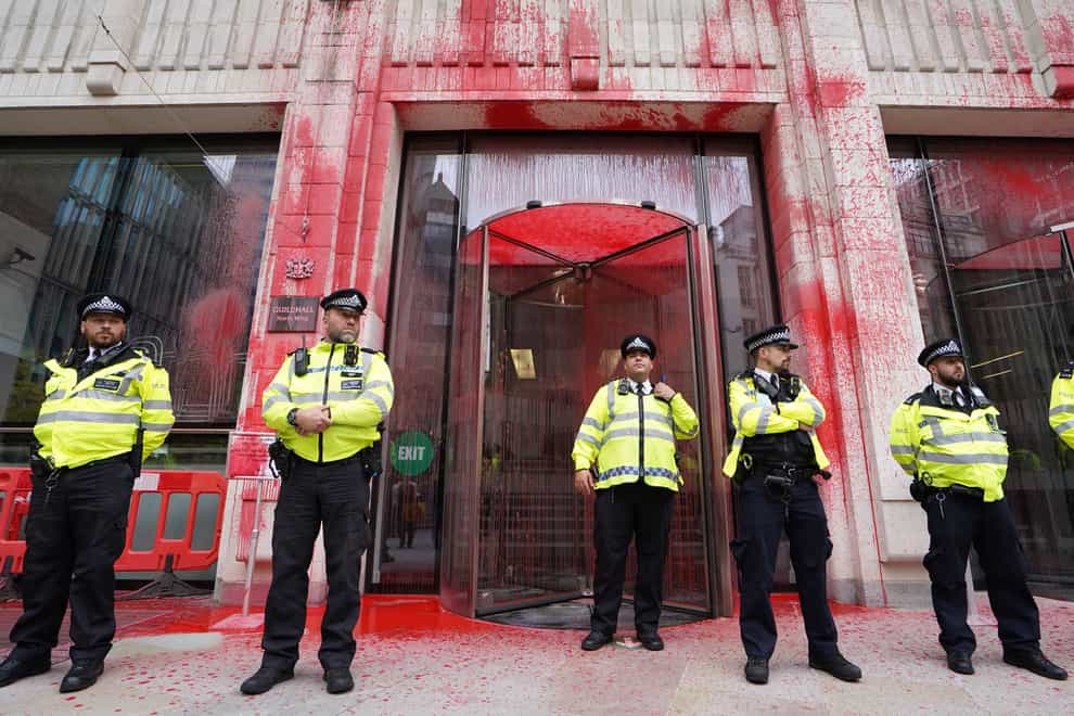 Police officers stand in front of the Guildhall, which has been daubed in paint (Stefan Rousseau/PA)