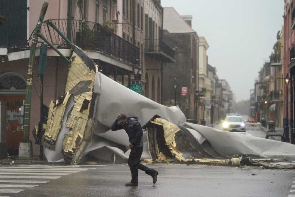 A man passes by a section of roof that was blown off of a building in the French Quarter by Hurricane Ida winds in New Orleans (Eric Gay/AP)