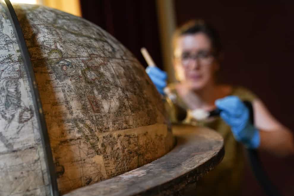 National Trust conservator Samantha Taylor cleans the rare Elizabethan globe (Andrew Matthews/PA)