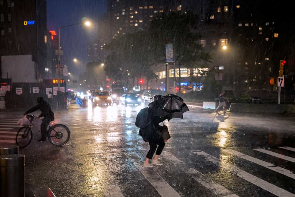 Pedestrians take cover near Columbus Circle in New York as the remnants of Hurricane Ida remained powerful while moving along the Eastern seaboard. (AP Photo/Craig Ruttle)