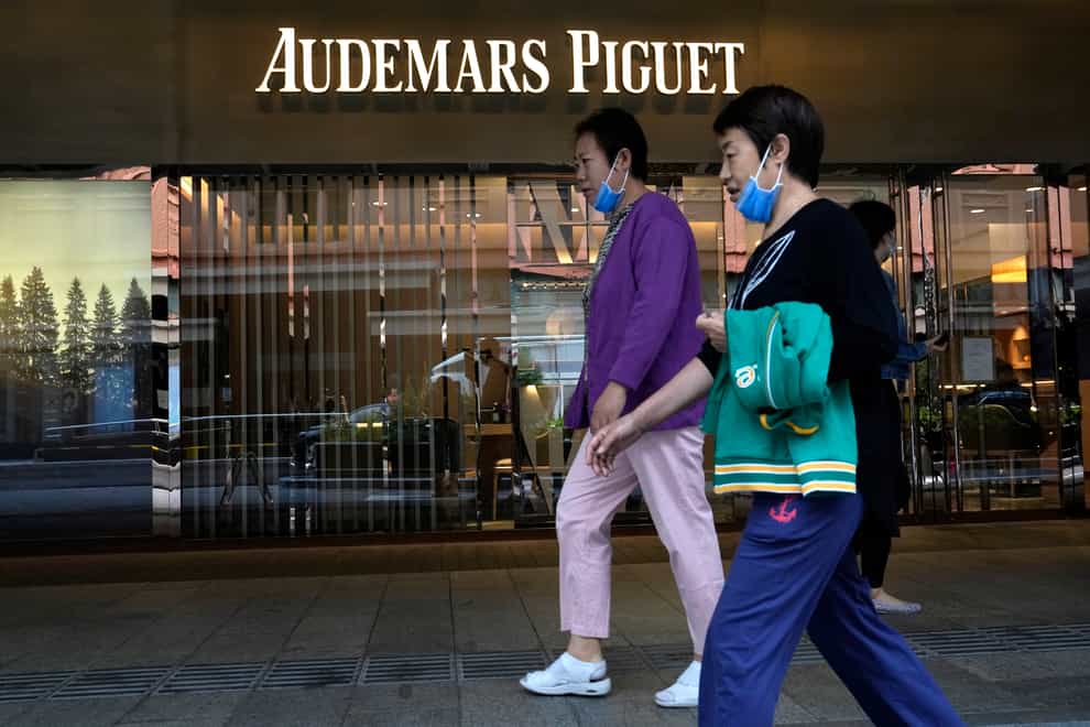 Visitors to a mall walk past the Audemars Piguet store in Beijing (Ng Han Guan/AP)