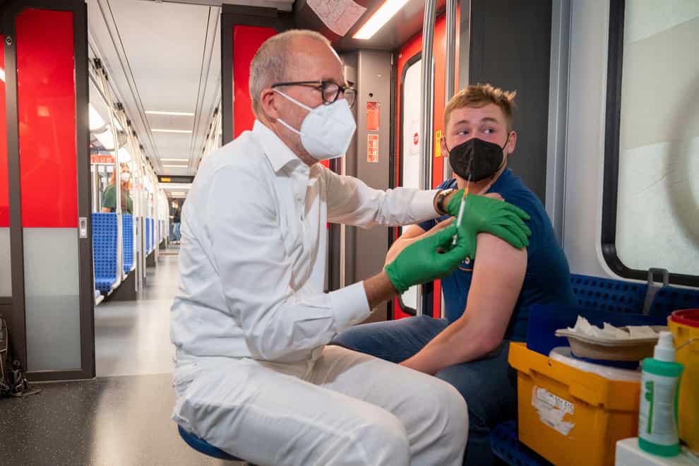 Christian Gravert, left, chief medical officer of the Deutsche Bahn, vaccinates a man with the Johnson & Johnson, or Janssen, vaccine in a special train of Berlin’s public transport S-Bahn, in which vaccination against Covid-19 are offered (Christophe Gateau/AP)
