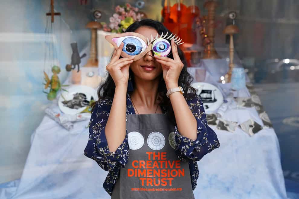 Student Roshni Patel holds two pieces of artwork in front of her eyes (Jonathan Brady/PA)